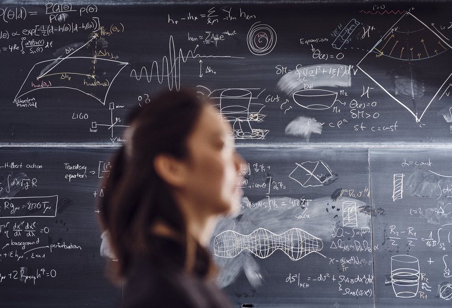 CoG PhD student Guangzi Xu photographed in front of a blackboard at the Niels Bohr Instiute